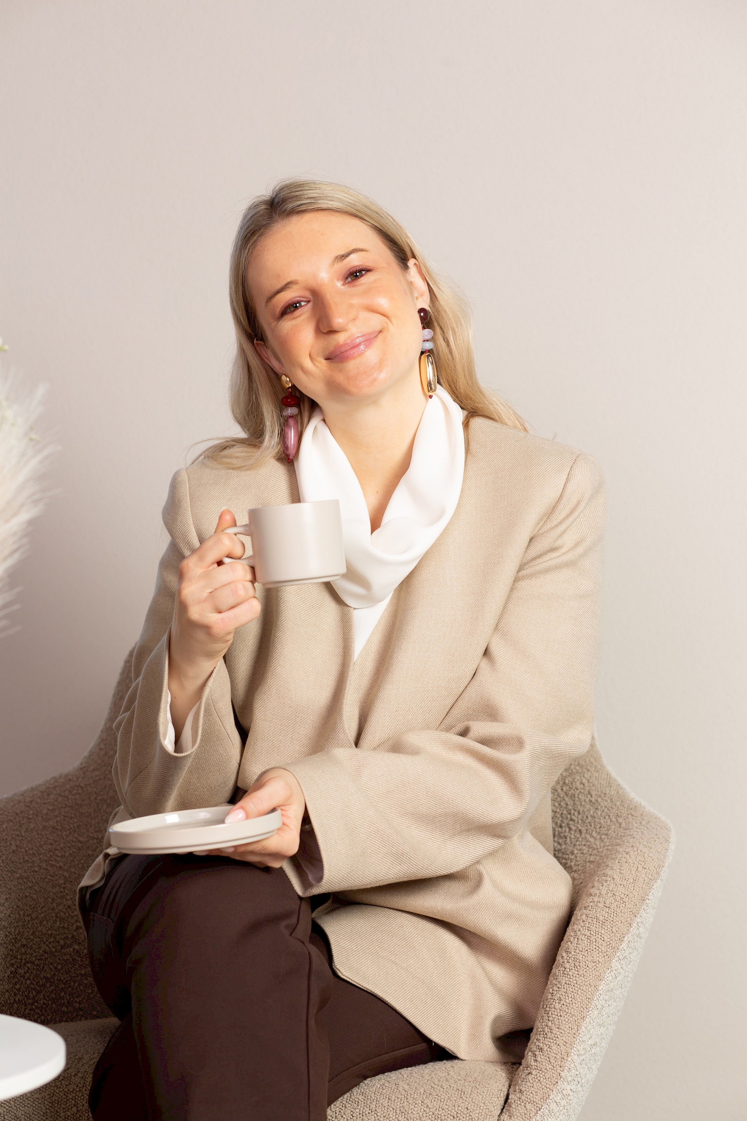 Person sitzt lächelnd mit Kaffeetasse - Social Emotion